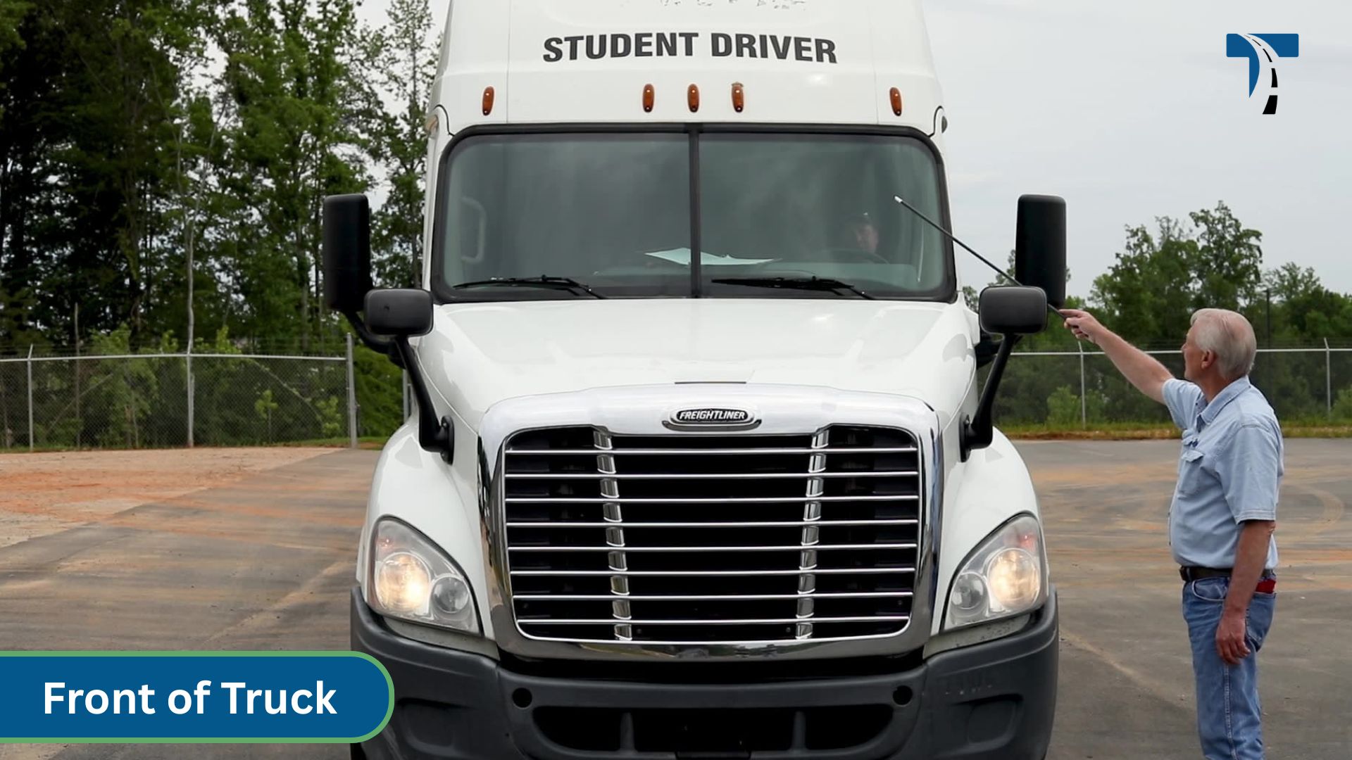 instructor pointing at front of semi tractor trailer cab