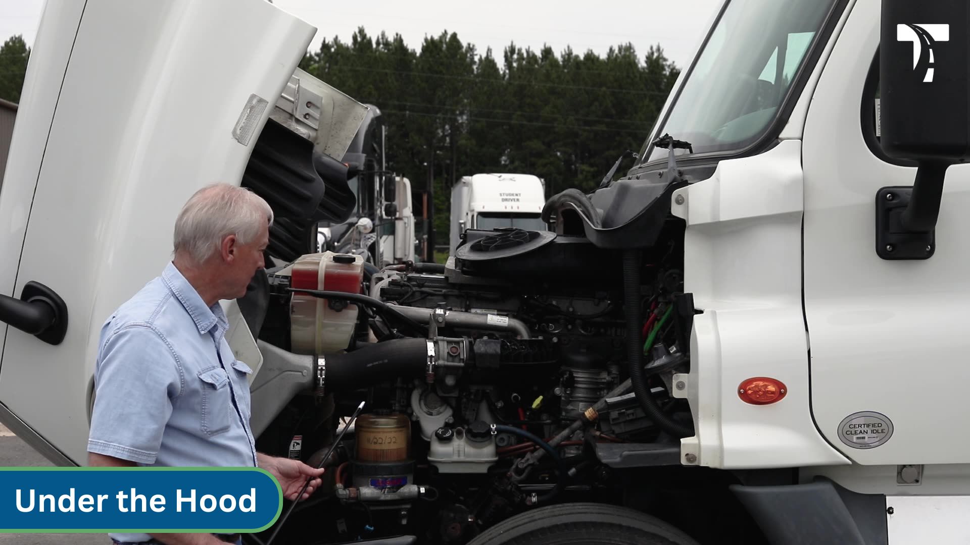 instructor pointing at parts under semi hood