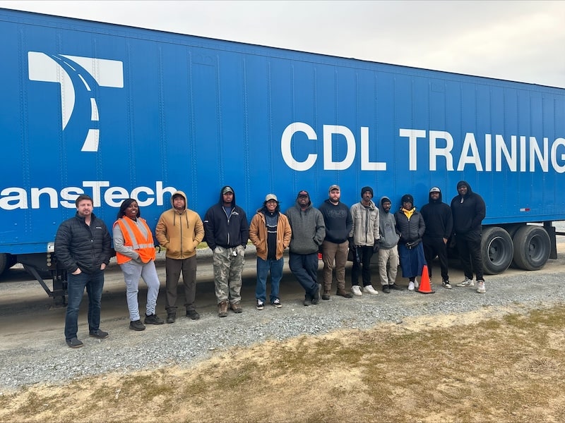 Students standing in front of blue TransTech semi truck trailer