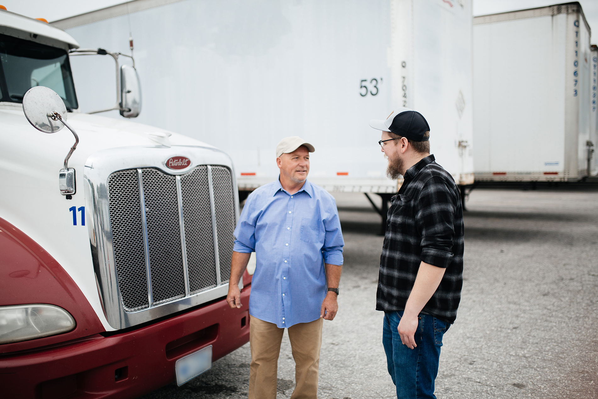 Two men standing in front of semi truck talking