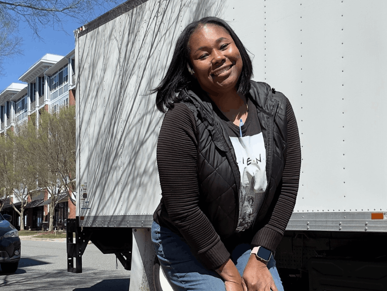 Tyronia smiling, crouched down in front of trailer