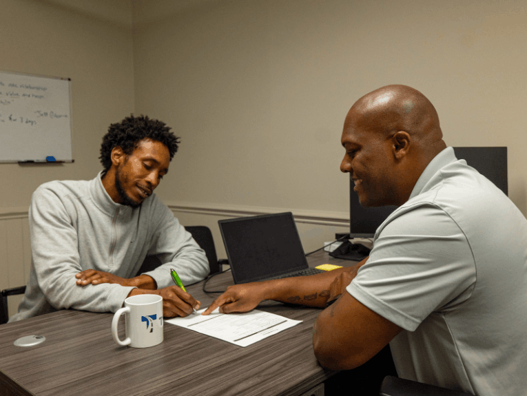 Admissions rep showing potential student paperwork while sitting at a desk