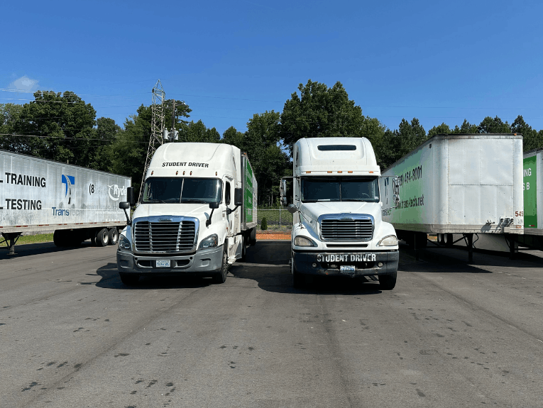 Two TransTech semi trucks parked in training lot, facing forward. Two trailers parked on each side.