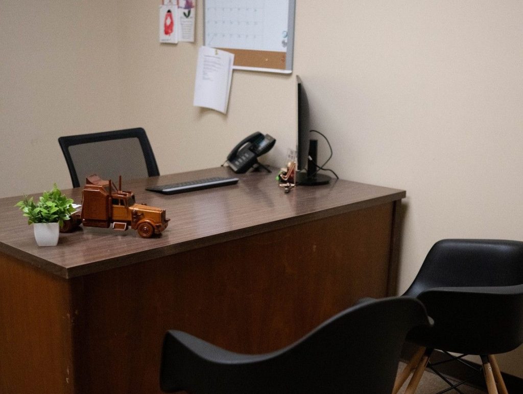 Charleston admissions desk with a toy semi truck and computer. Two chairs in front.