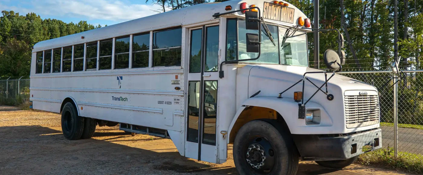 TransTech school bus parked in empty gravel parking lot
