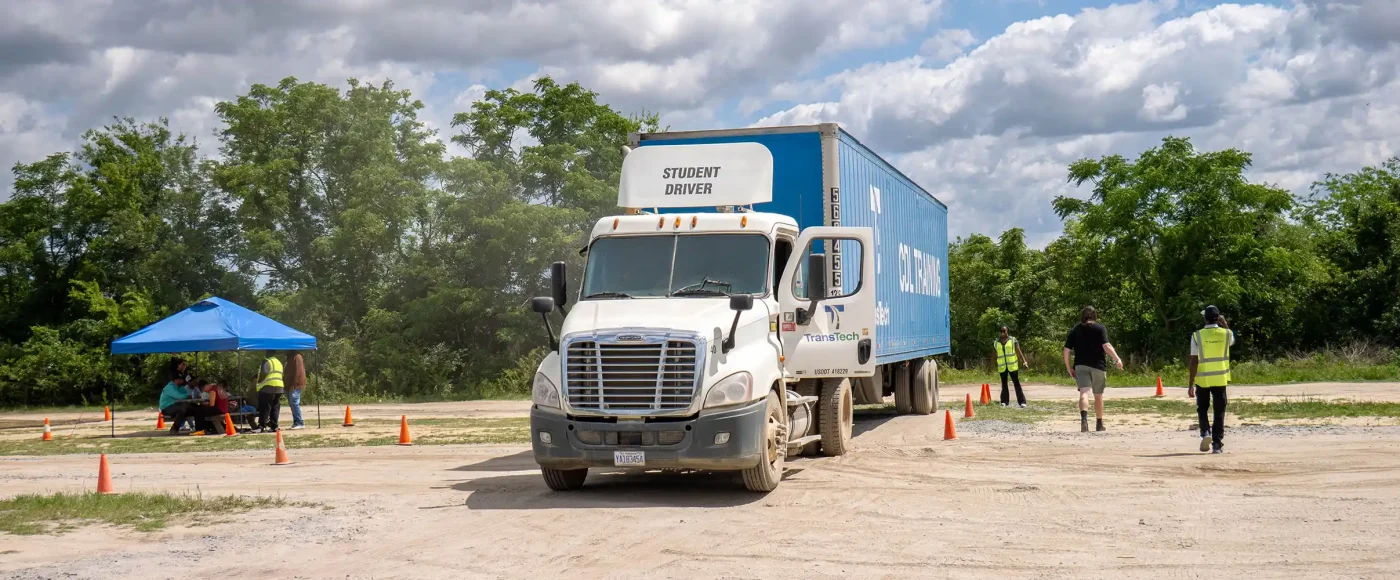 Fayetteville campus training yard with a semi truck and students sitting under a tent