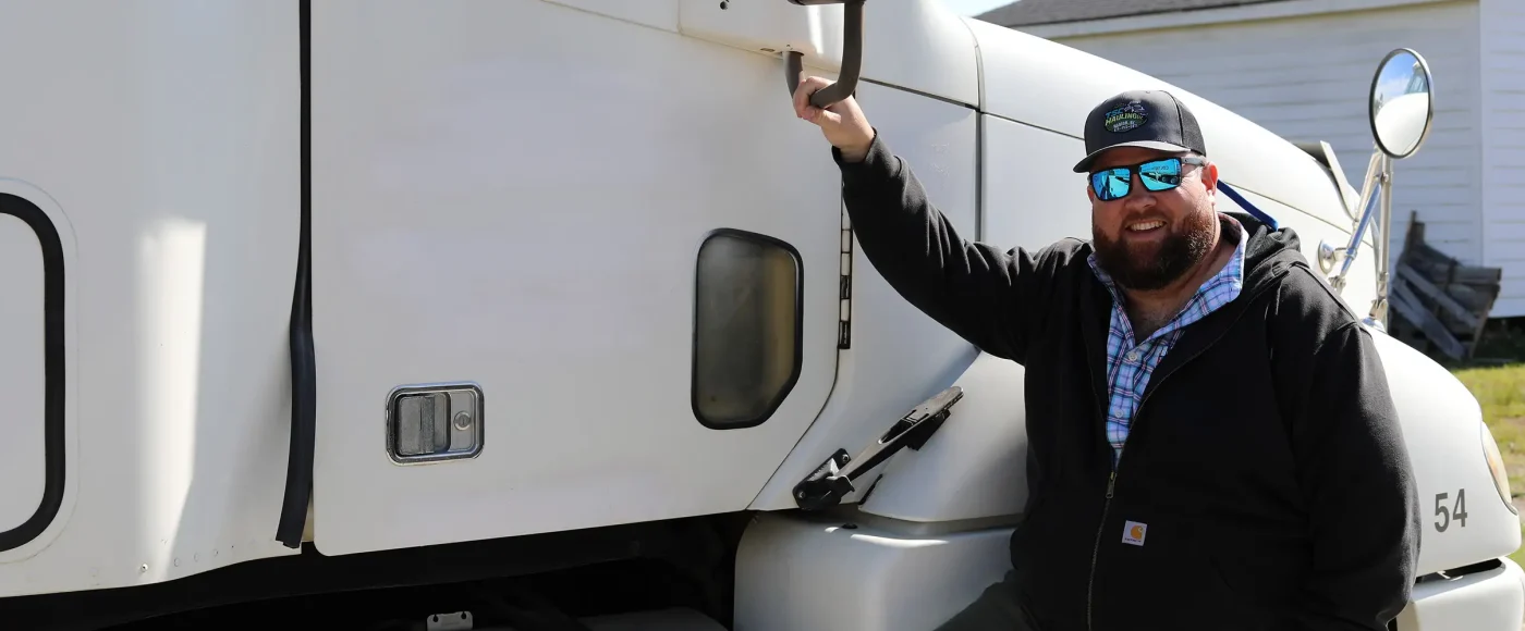 Semi truck driving smiling and holding onto the bottom of semi truck mirror