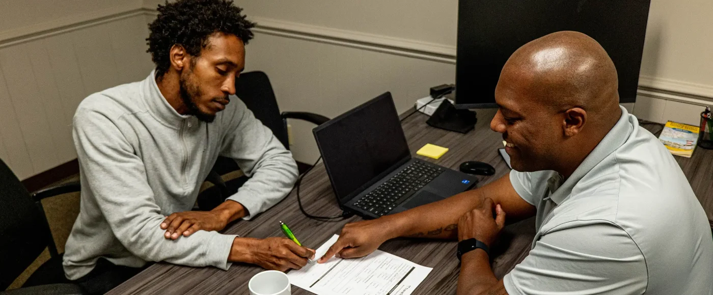 Admissions representative pointing to paper with a student sitting at the desk