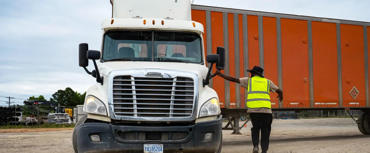 TransTech CDL instructor in safety vest spotting a student driver in a semi-truck during yard training