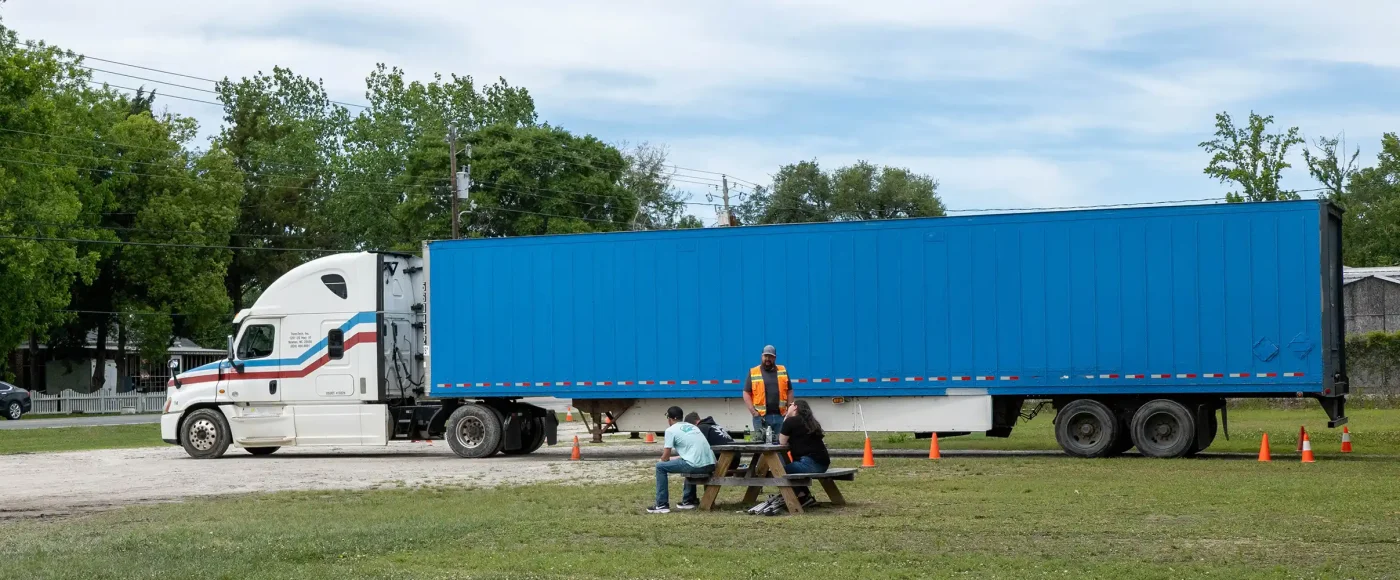 TransTech CDL instructor and students taking a break at a picnic table beside a semi-truck in Wilmington