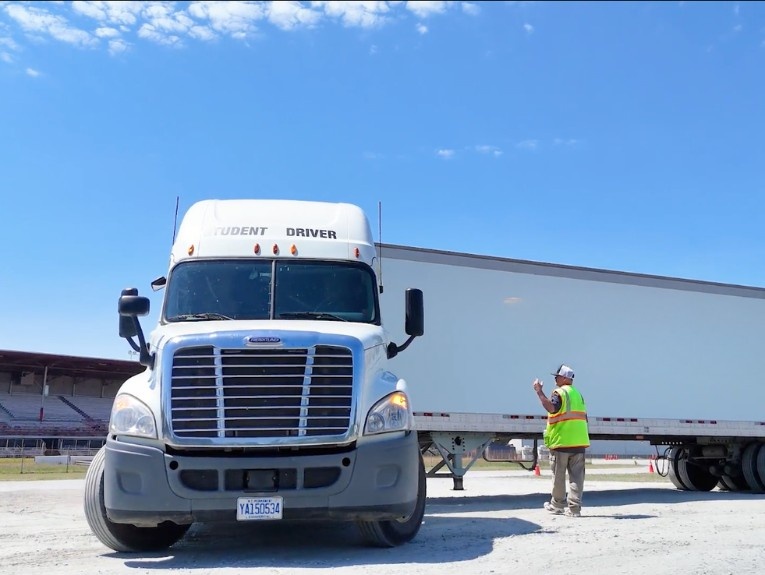 Front view of TransTech semi truck in training yard. Instructor directing the driver.